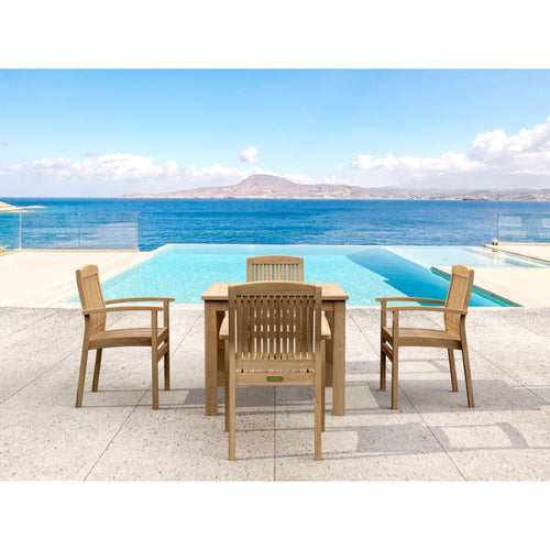 A 5-piece outdoor dining set made of light natural teak wood, featuring a rectangular table and four matching armchairs, arranged on a stone patio with an infinity pool and ocean view in the background.
