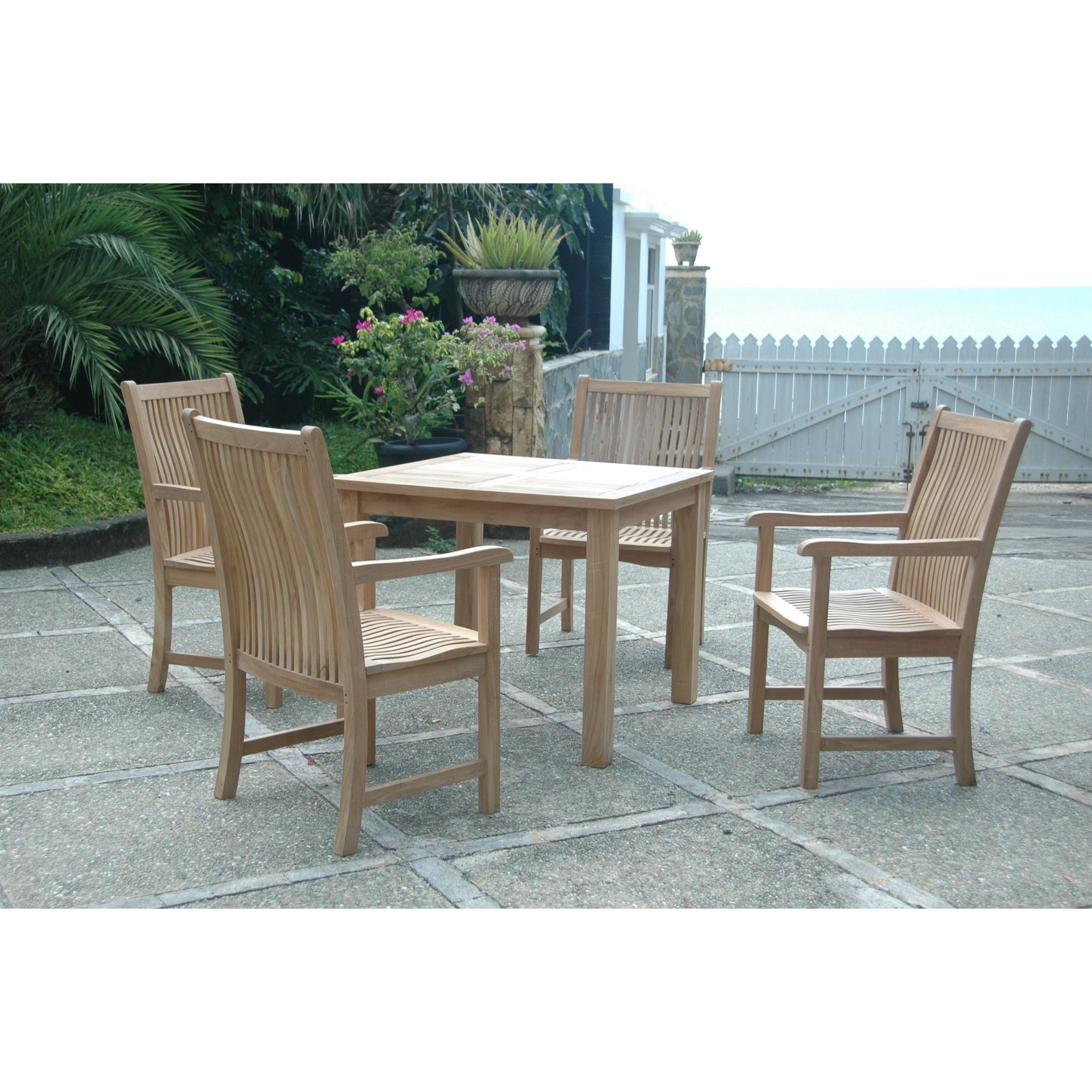A 5-piece outdoor dining set consisting of a rectangular slat-top table and four matching armchairs, shown on a stone patio with garden plants and a white fence in the background.