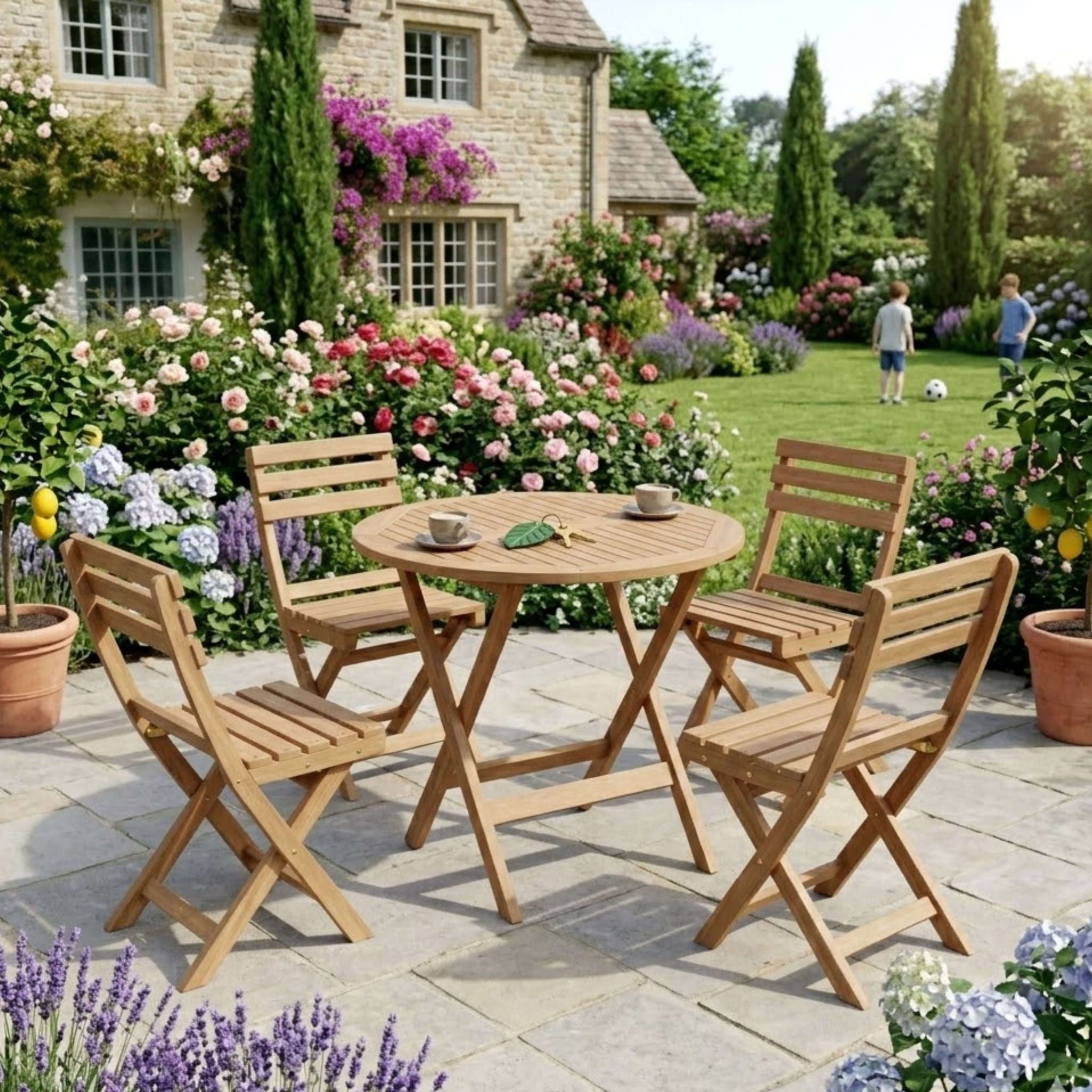 Wooden garden table and chairs set in a garden with flowers and a house in the background