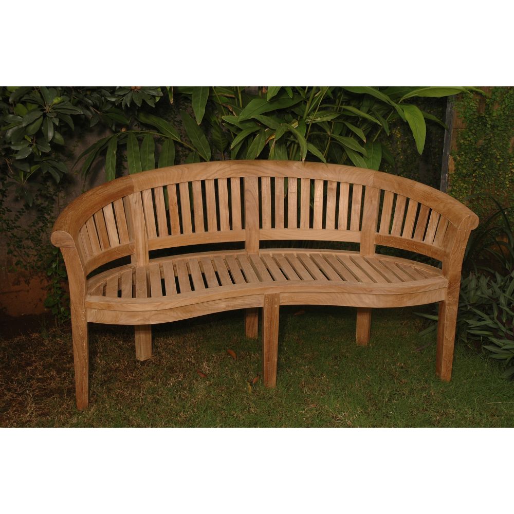 A curved outdoor wooden bench made of natural teak wood, set on a grassy lawn with a background of green garden foliage.