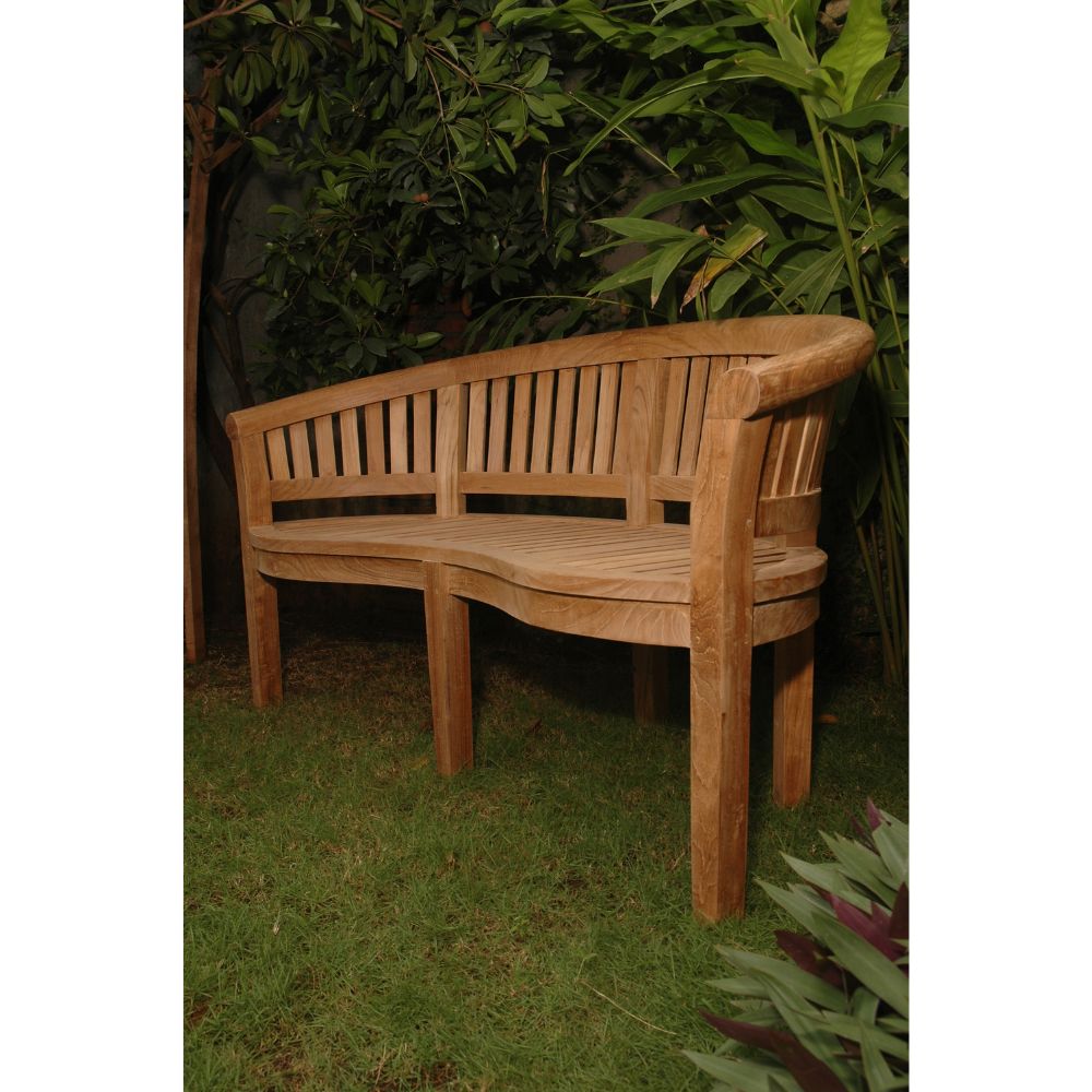 A curved wooden garden bench with a slatted backrest, shown outdoors on grass with leafy plants in the background.