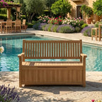 A wooden outdoor bench with a storage compartment base, positioned on a stone patio next to a swimming pool in a luxurious garden setting.