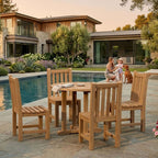 Wooden outdoor dining set by a pool with a modern house in the background