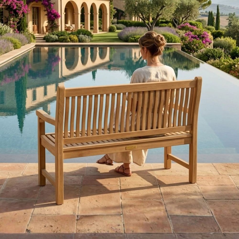 Person sitting on a wooden bench by a pool with a scenic garden view