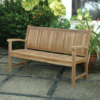 Wooden bench on a patio with plants in the background