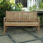 Wooden bench on a stone patio with plants in the background