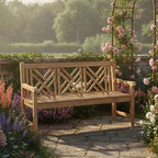 A wooden garden bench with a geometric lattice backrest, set on a stone patio in a lush garden with pink roses and flowers.
