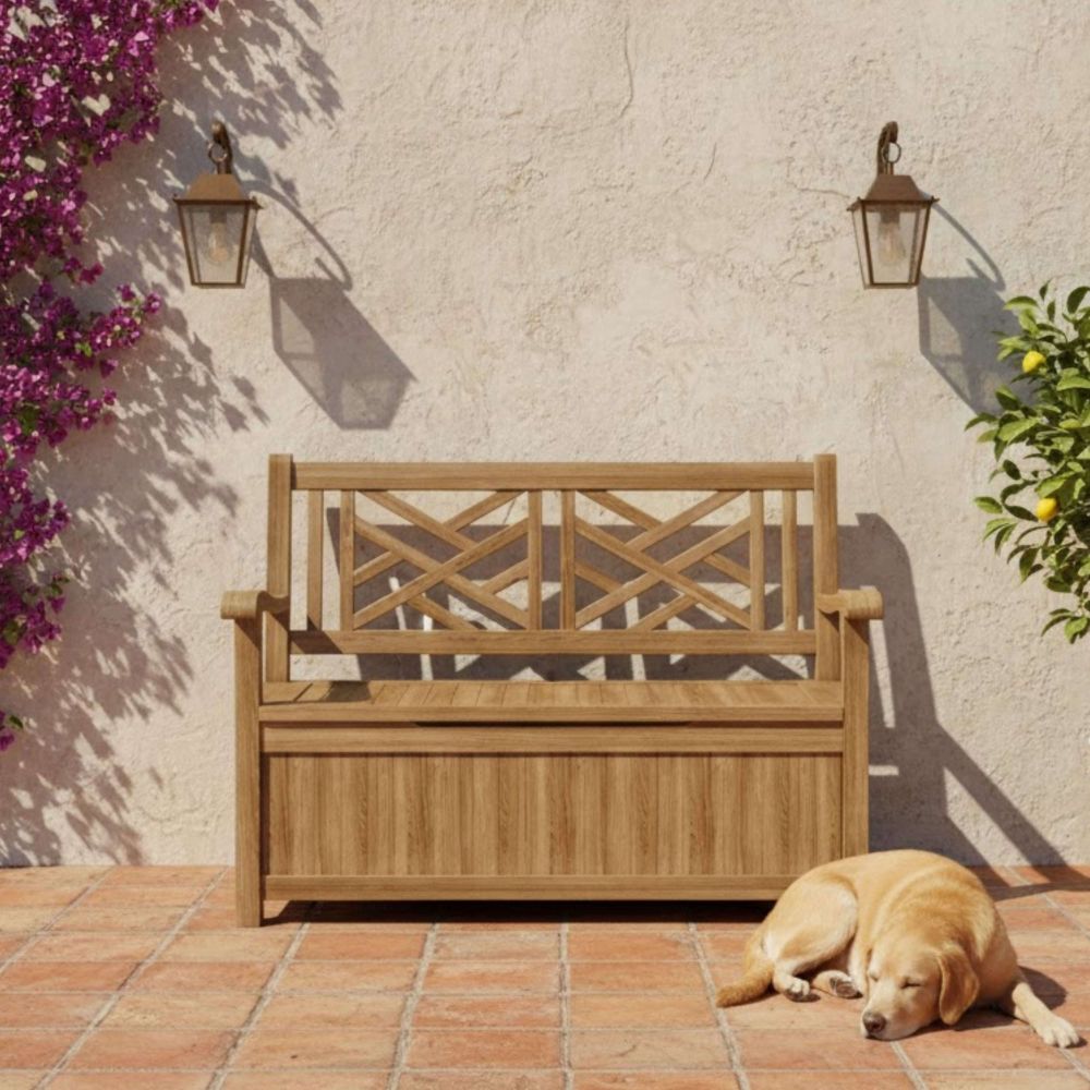 A wooden outdoor storage bench with a slatted backrest and front panel, placed on a terracotta tile patio against a stucco wall. A golden retriever lies at the bench's right side, and purple flowers and greenery frame the scene.