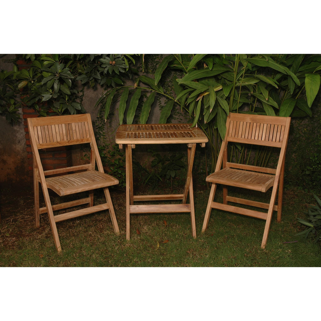 A three-piece outdoor wooden patio set consisting of two folding chairs and a small slatted side table, placed on grass in front of a leafy green wall.