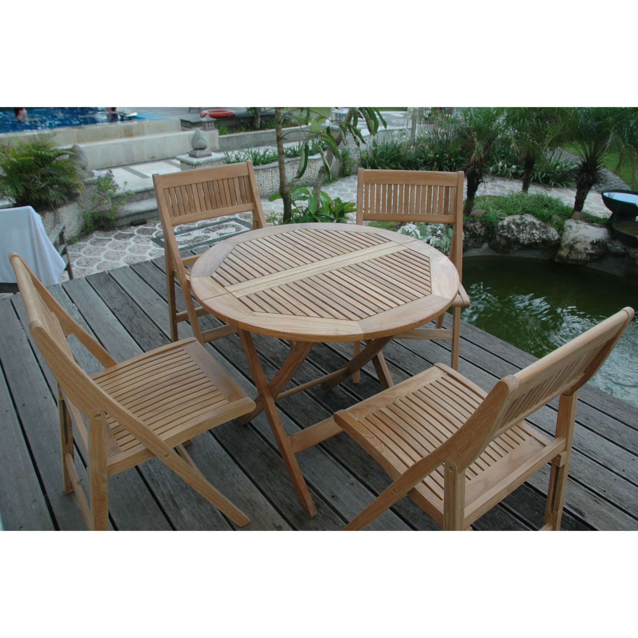 Wooden outdoor table and chairs set on a deck with a garden background