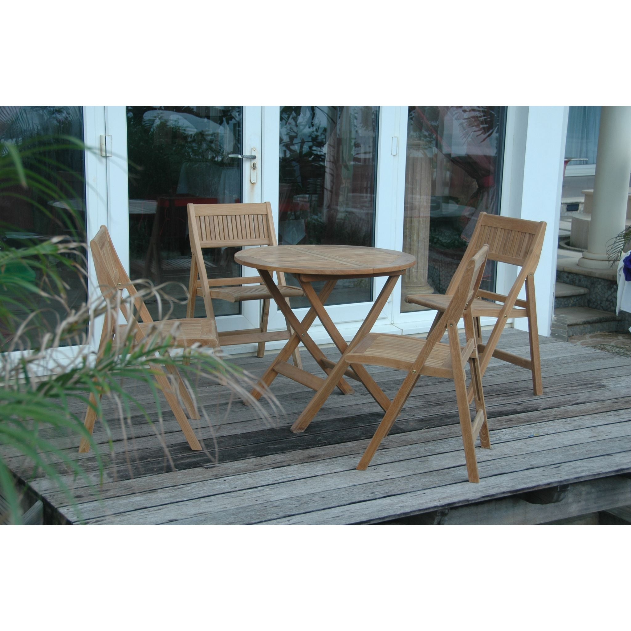 Wooden outdoor table and chairs on a wooden deck with a glass door in the background.