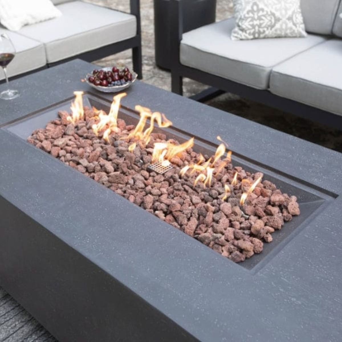 Fire pit table with flames and decorative rocks on a patio setting