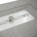 A stainless steel linear guide rail assembly with a central perforated metal block and mounting brackets, set into a gray textured surface.