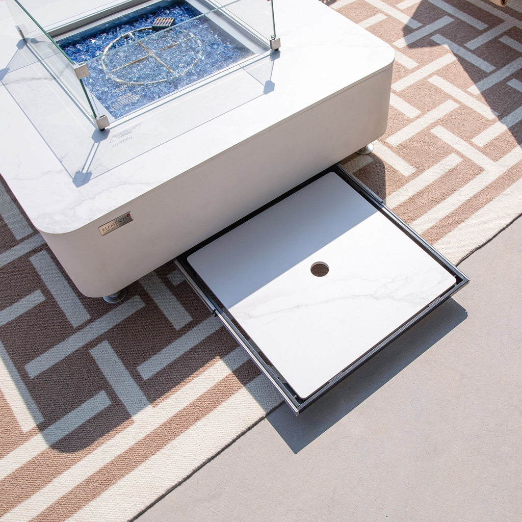 Outdoor coffee table with glass top and storage drawer on a patterned rug
