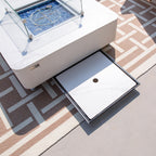 Outdoor coffee table with glass top and storage drawer on a patterned rug