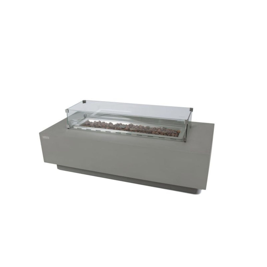 A modern outdoor fire pit with a rectangular gray base, a clear glass wind guard, and visible brown decorative stones inside, shown on a plain white background.