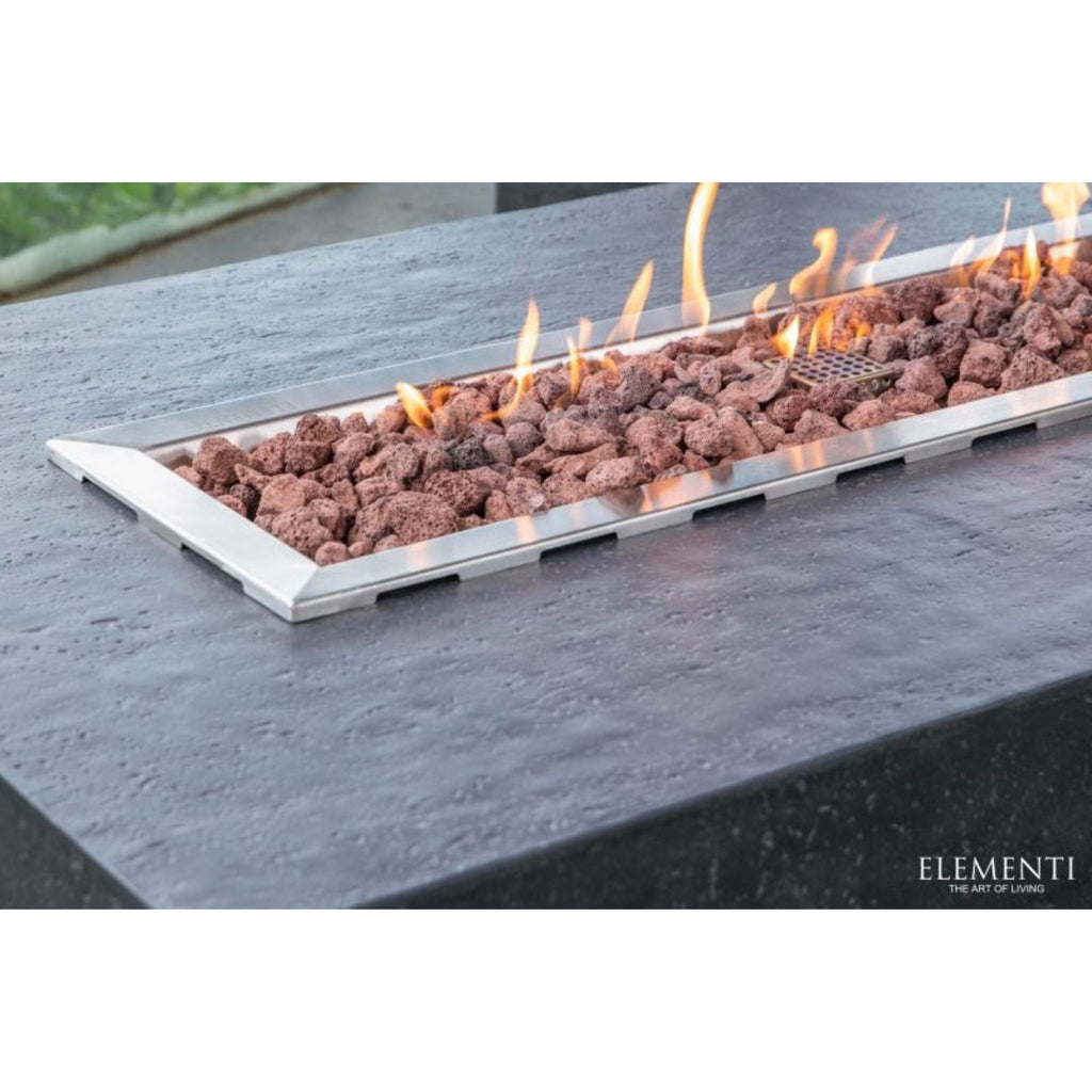 Elementi outdoor rectangular fire pit with a stainless steel frame, filled with brown lava rocks and active orange flames, set into a dark stone table.