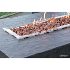 Elementi outdoor rectangular fire pit with a stainless steel frame, filled with brown lava rocks and active orange flames, set into a dark stone table.