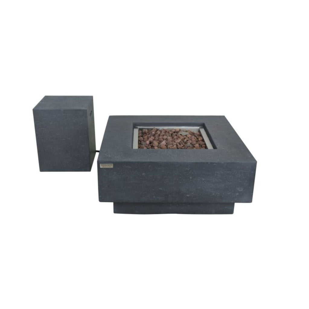 A modern outdoor fire pit table made of dark gray stone, featuring a square base filled with brown decorative stones and a separate matching dark gray side pedestal, shown on a plain white background.