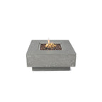 A square concrete fire pit with a lit flame, filled with dark decorative stones, shown against a solid white background.