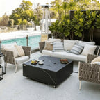 Outdoor patio setup with fire pit table, chairs, and a pool in the background.