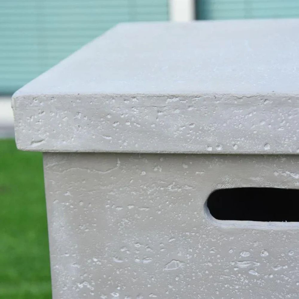 Close-up of a textured gray concrete bench with a blurred green background
