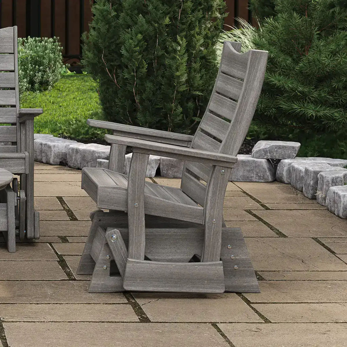 Gray wooden chair on a patio with greenery in the background