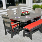 Outdoor patio set with gray table and chairs with red cushions on a stone patio.