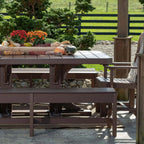 Outdoor wooden furniture set with a table and benches on a patio, surrounded by greenery.