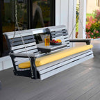 Wooden porch swing with yellow cushion on a deck, featuring a drink and fruit bowl.