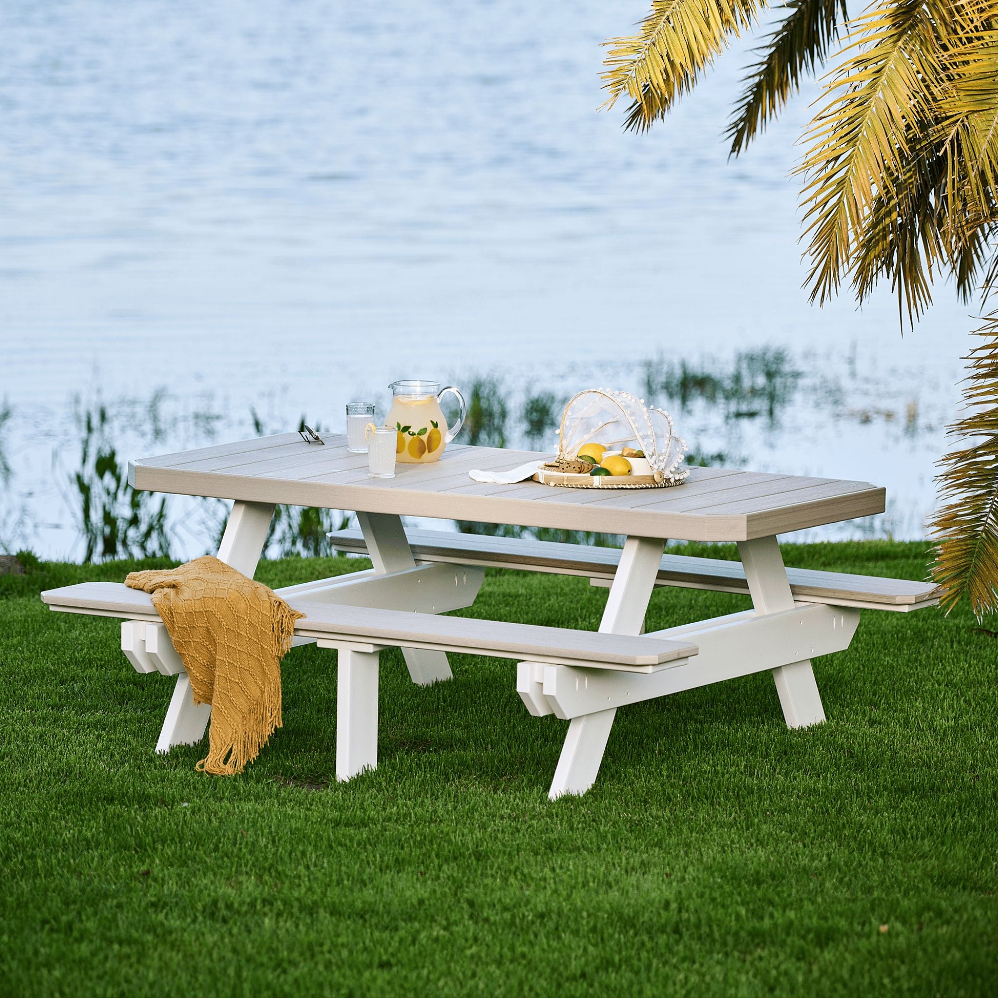 Picnic table with drinks and snacks by a body of water