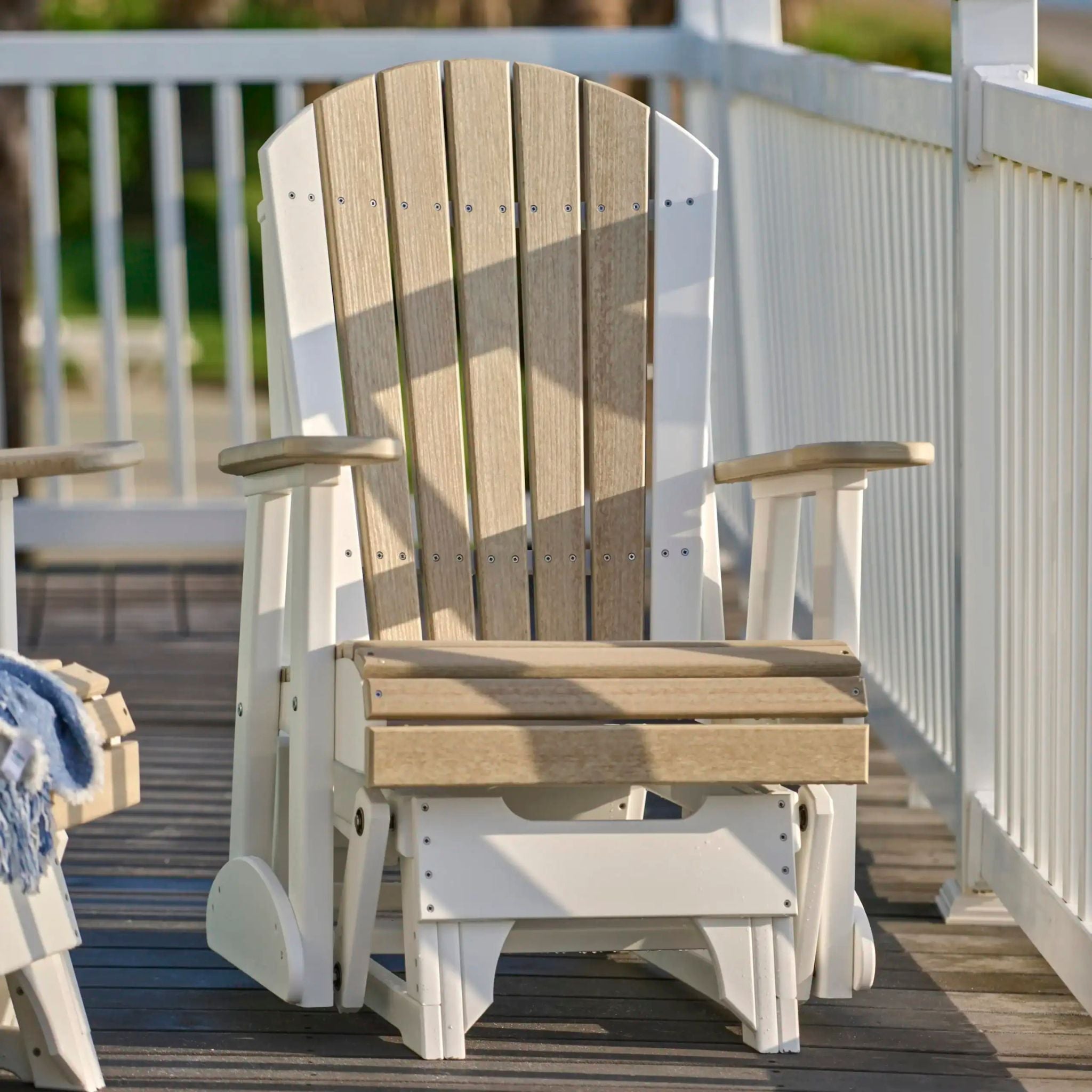 Wooden glider chair on a wooden deck with a white railing.