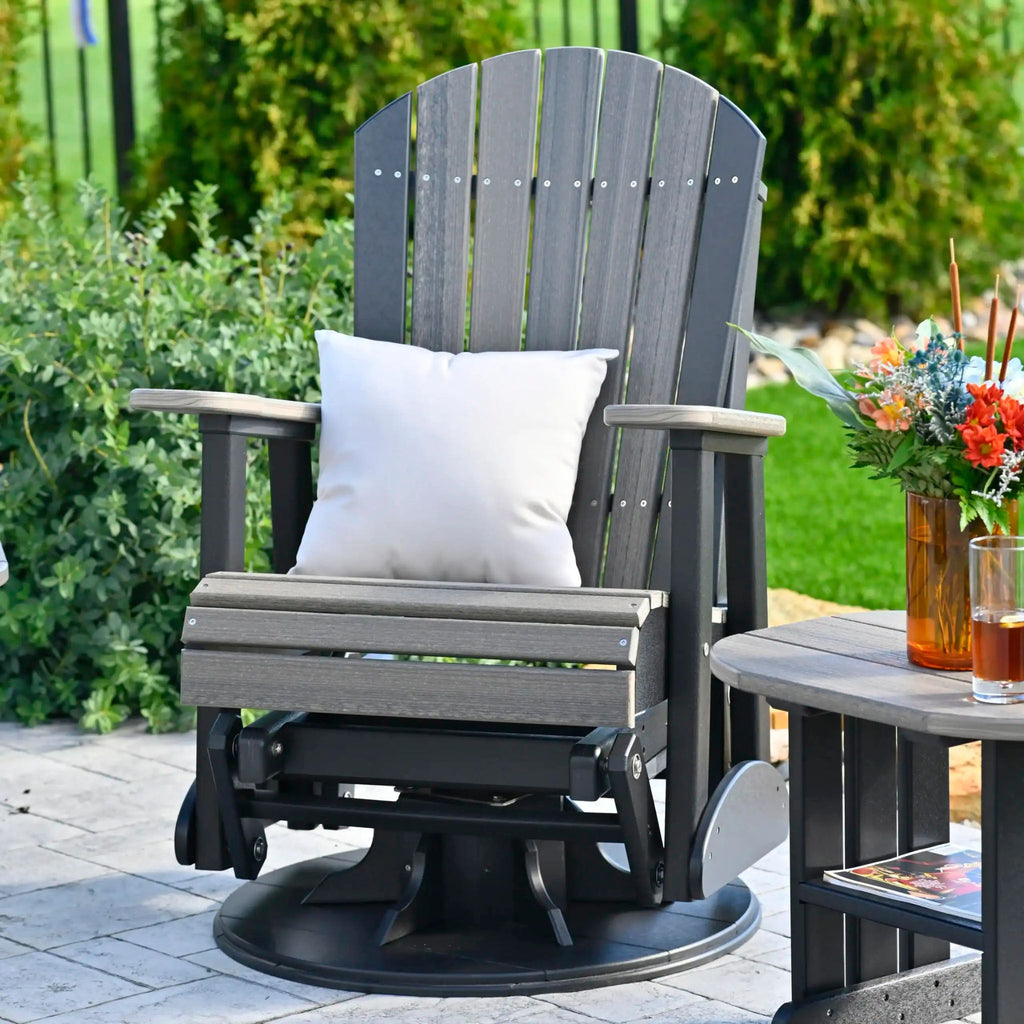 Gray outdoor chair with a white pillow on a patio with a small table and flowers.
