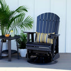 Black Adirondack chair with a striped pillow on a patio with plants and a small table.