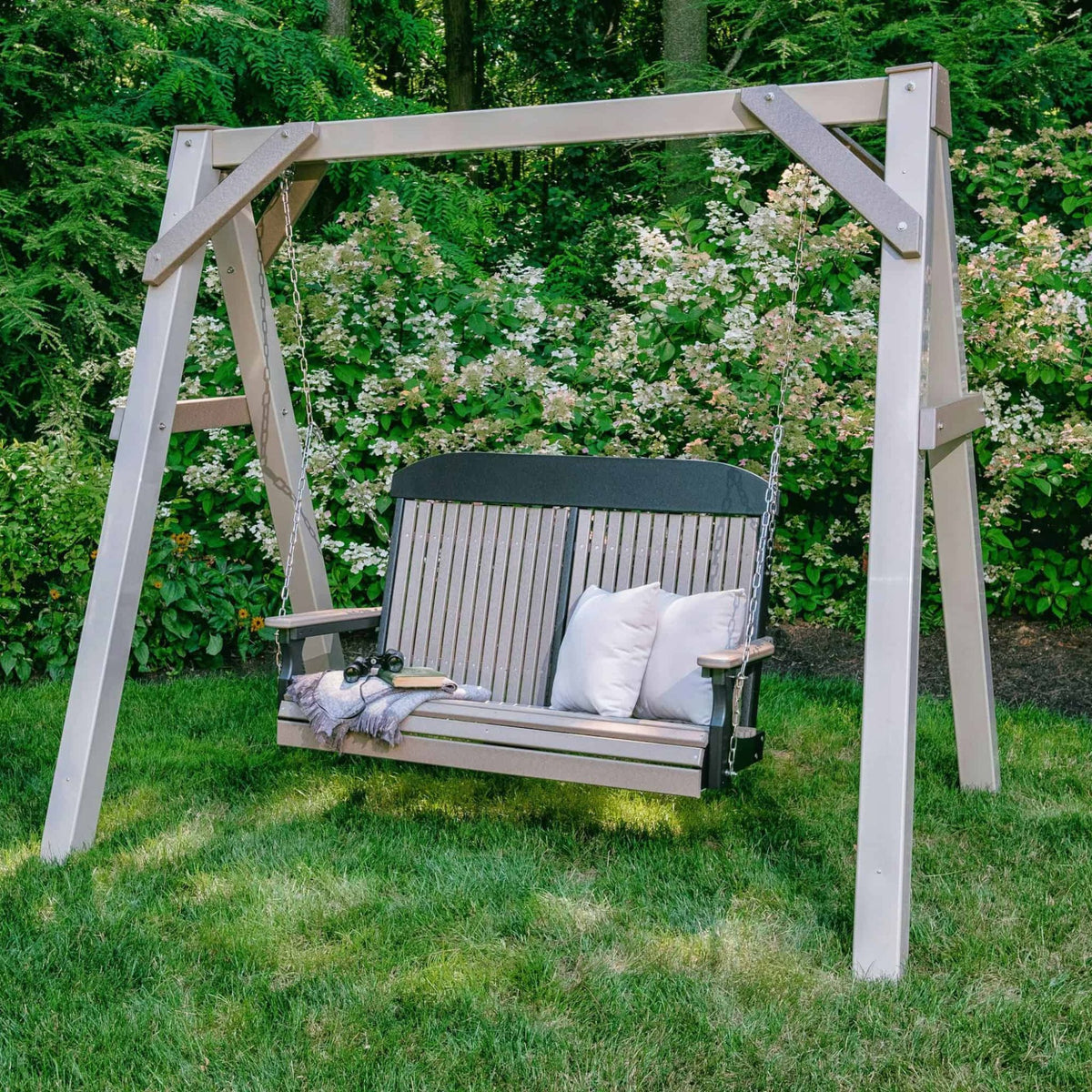 Wooden swing with white cushions in a garden setting