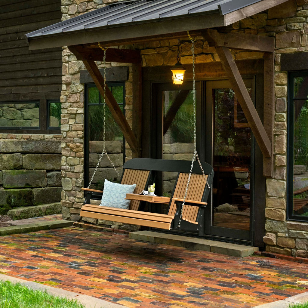 Wooden swing bench with cushions in front of a stone building.