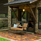 Wooden swing bench with cushions in front of a stone building.