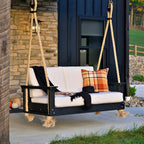 Black wooden swing with white cushions and colorful pillows on a porch.