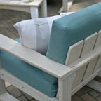 Outdoor chair with teal and white cushions on a patio.