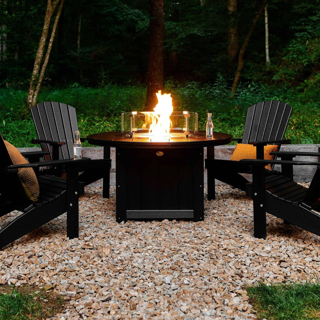 Fire pit table with chairs around it in a wooded area