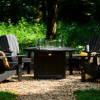 Outdoor setting with a fire pit table and Adirondack chairs in a garden.