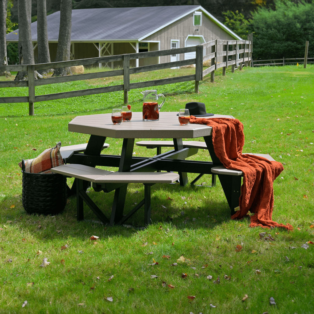 Outdoor picnic setup with a table, chairs, and a blanket on a grassy field.