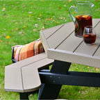 Outdoor picnic table in a grassy yard with a glass pitcher and glass of iced drink on the table.