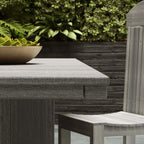 Wooden outdoor table and chair set with greenery in the background