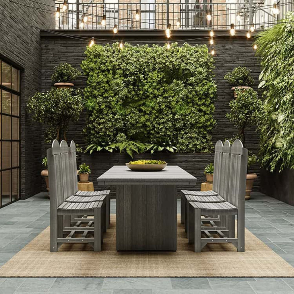 Outdoor patio set with gray chairs and table against a green wall.