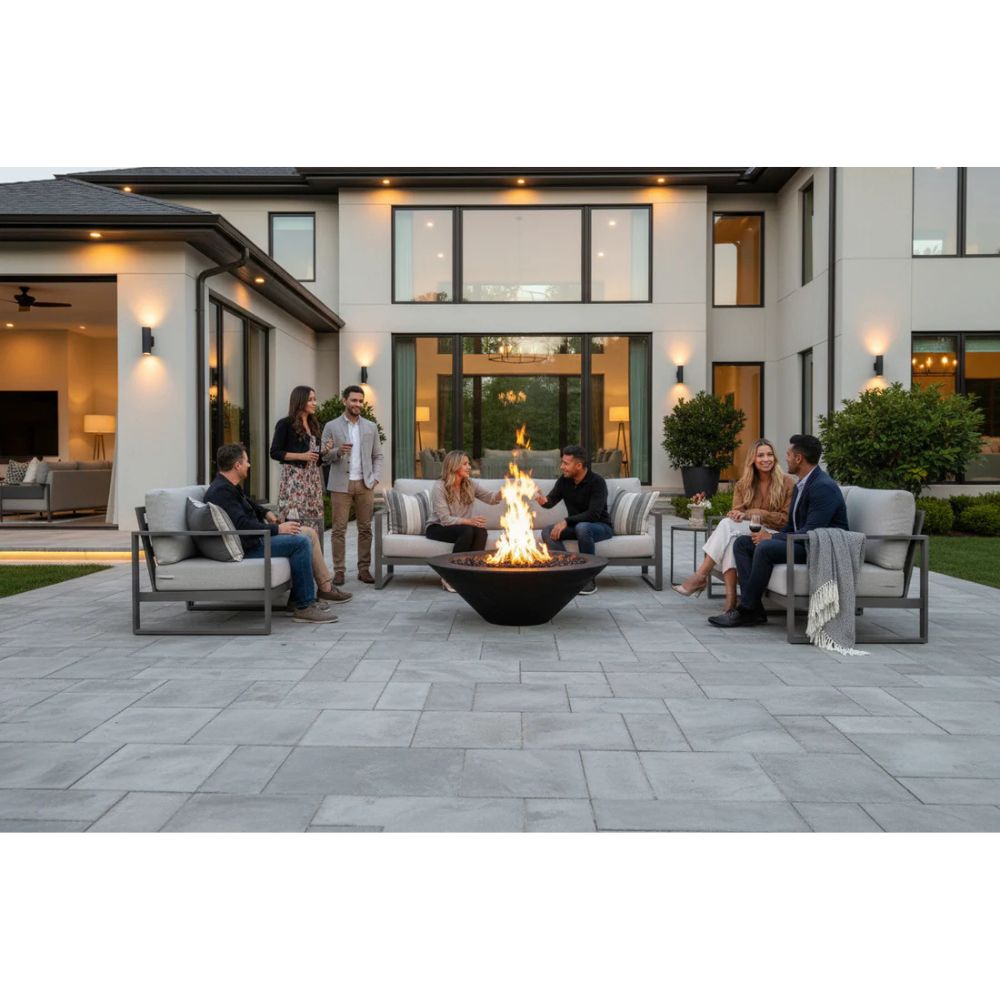 Group of people gathered around a fire pit on a patio in front of a modern house.