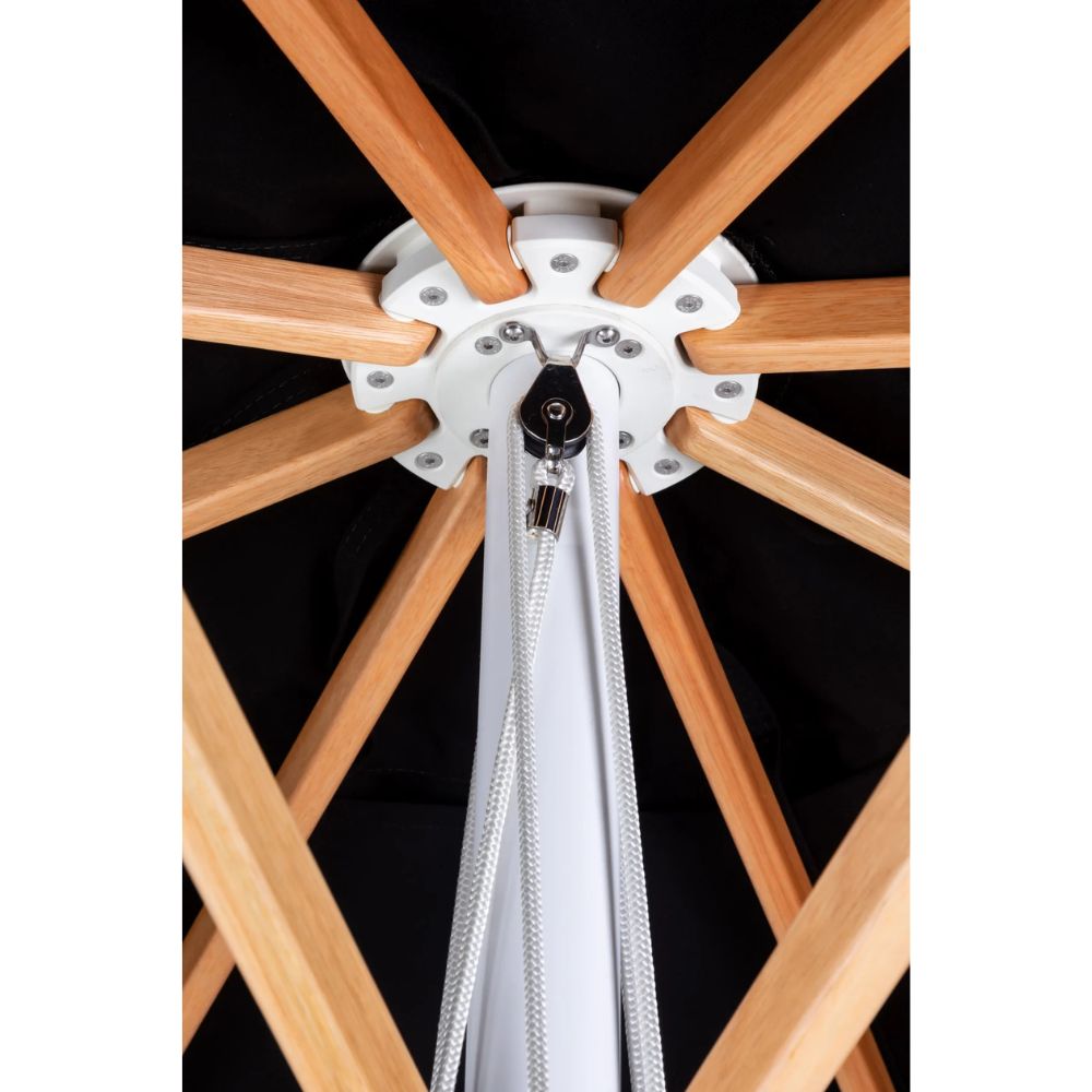 Close-up of a canopy attachment point with light natural wood radial ribs, a white central hub, and white hanging straps against a black canopy background.