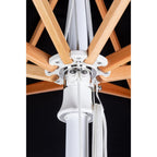 Close-up detail of an umbrella frame showing the central white metal hub, wooden ribs, and white rope pulls against a black background.