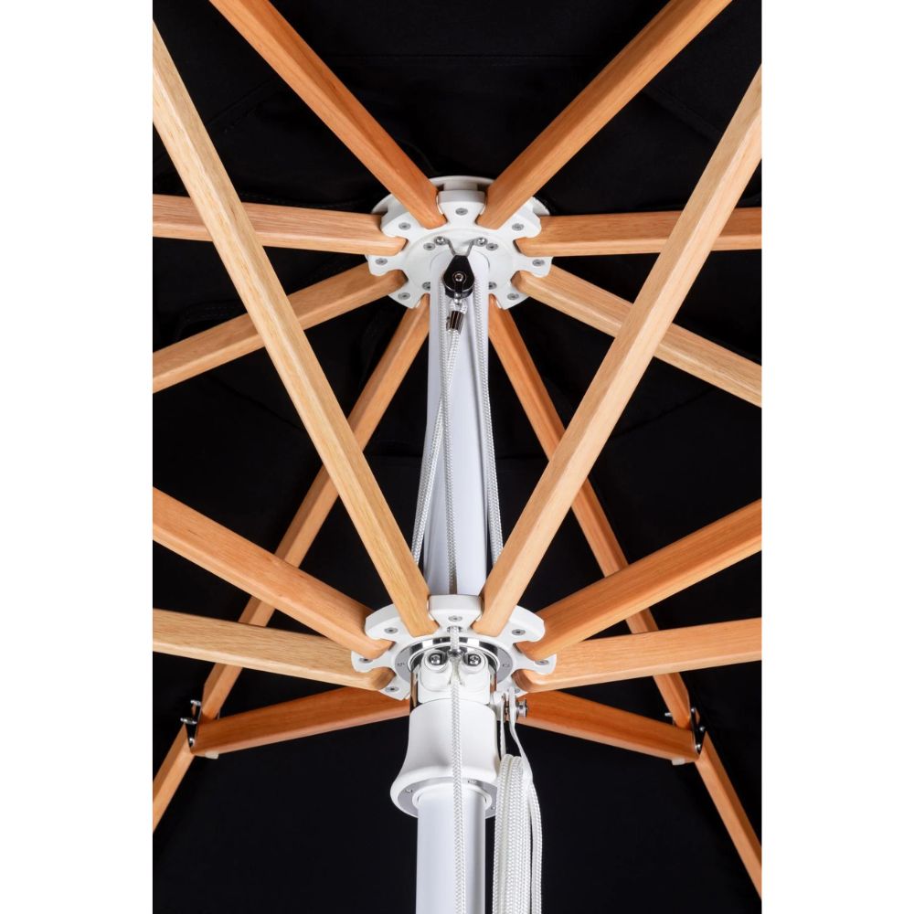 Close-up of a patio umbrella canopy and frame, showing a black fabric canopy, natural wood ribs, and a white central pole and hardware.