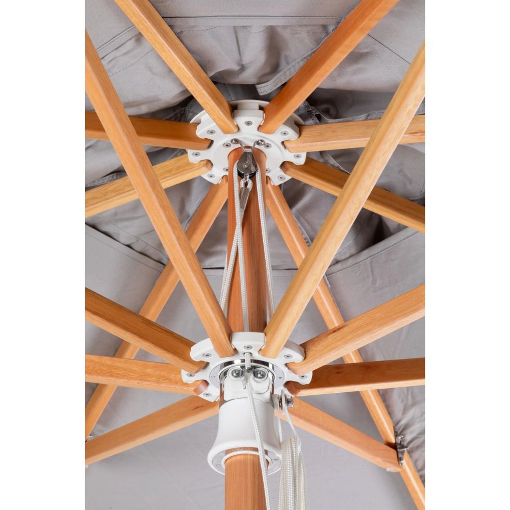 Close-up of the underside of a patio umbrella showing light natural wood ribs, white metal hardware, and a gray fabric canopy.